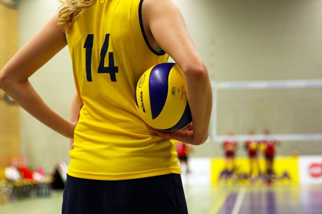 Girl holding volleyball in sports centre