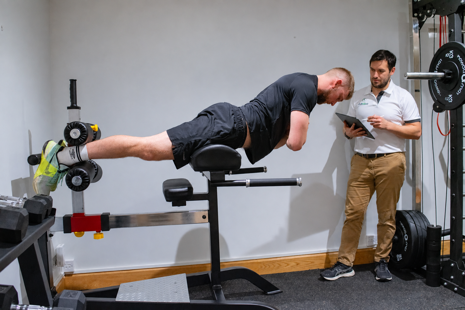 Trainer overseeing a patient’s back extension exercise in the Just One Body gym