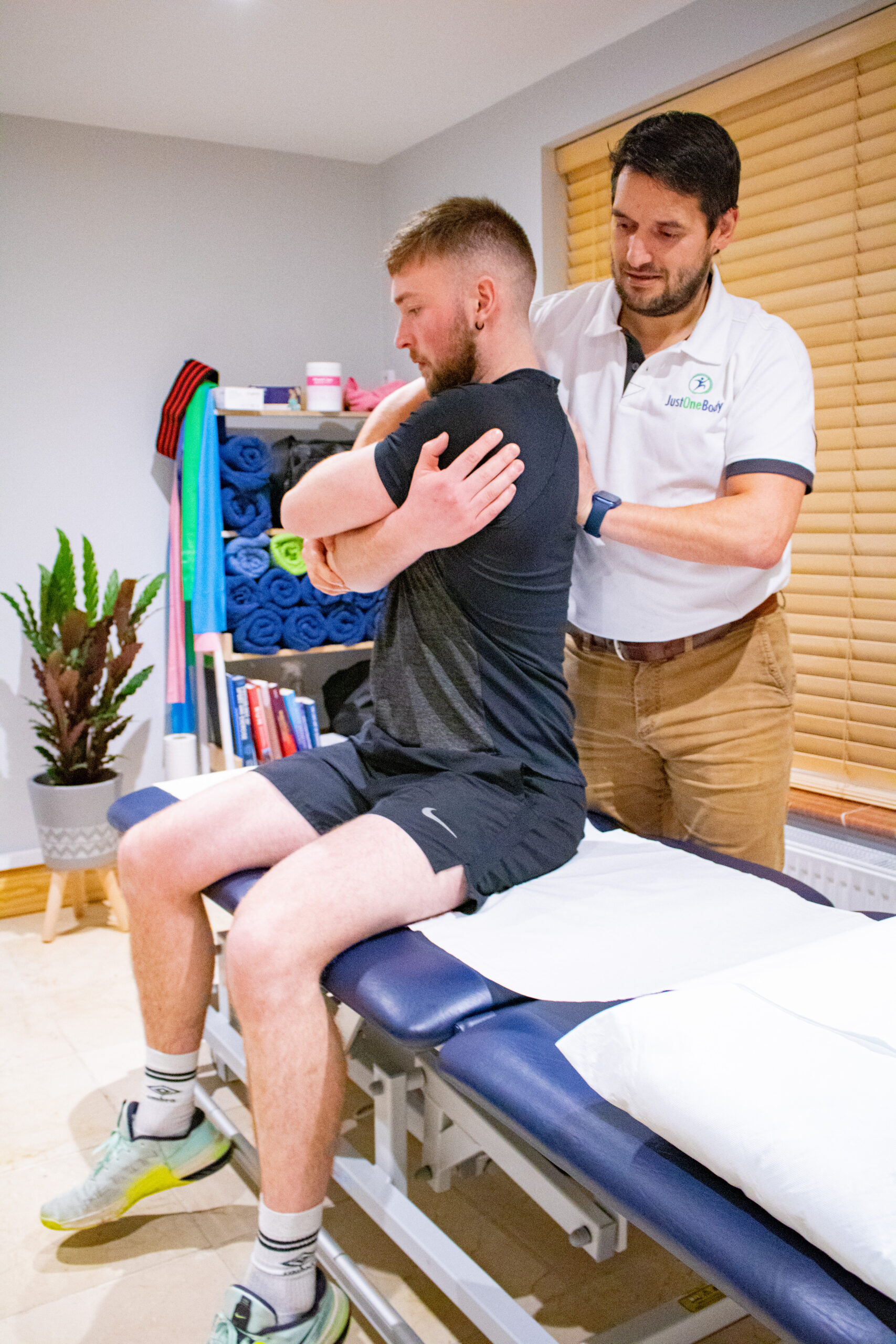 Kieran Lowe assessing a patient's spine while he sits on the treatment table