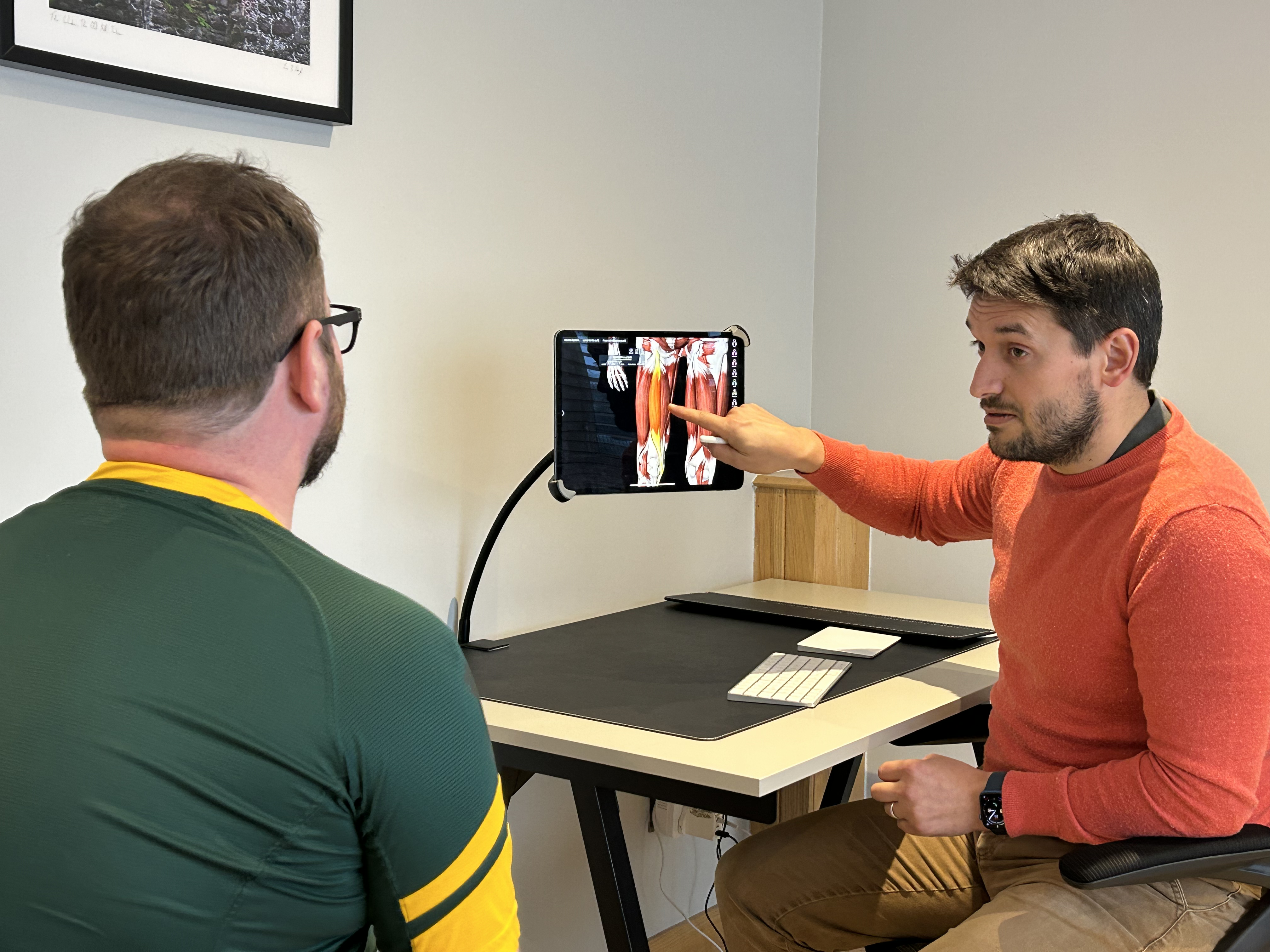 Kieran Lowe explaining a muscle diagram to a patient on a screen