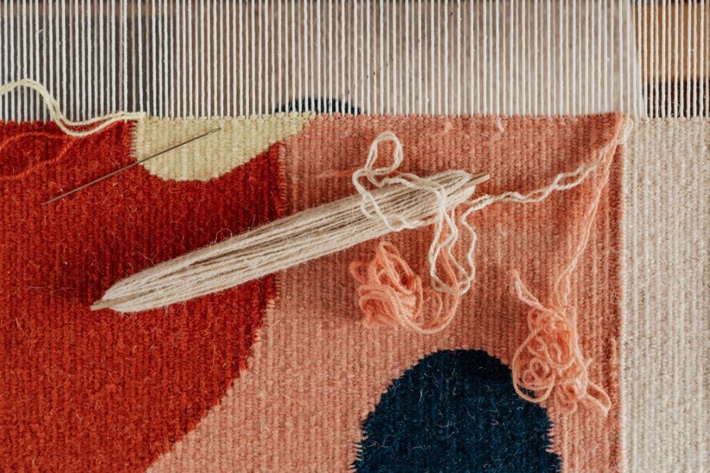 Hands weaving on a loom