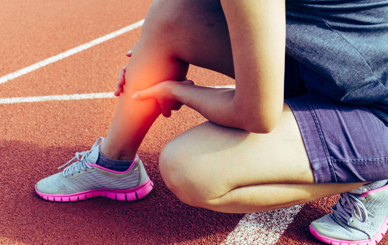 Runner on a track holding her lower leg