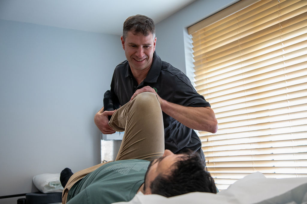 An osteopath checking a patient’s hip movement at Just One Body, New Ross